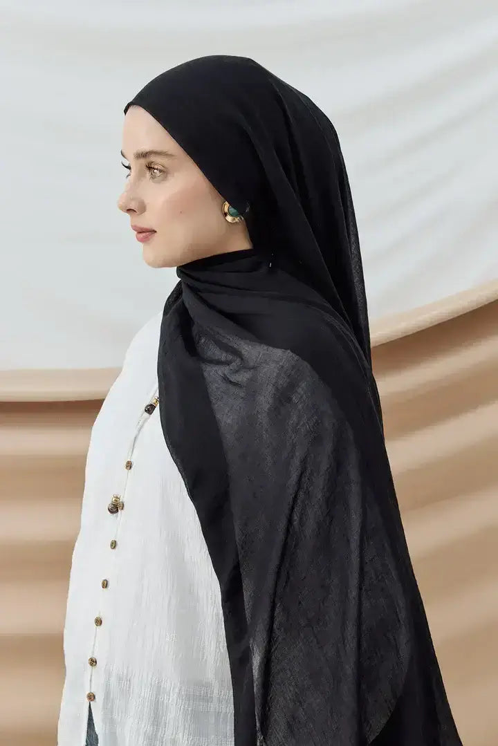 "Aya Şal Serisi siyah şal, hafif dokusu ve mat duruşuyla sade ve zarif bir görünüm sunuyor."