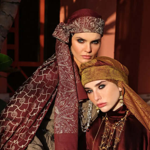 "Etnik desenli bord ve hardal tonlarında şal takan iki kadın model geleneksel stil ile kamera karşısında"