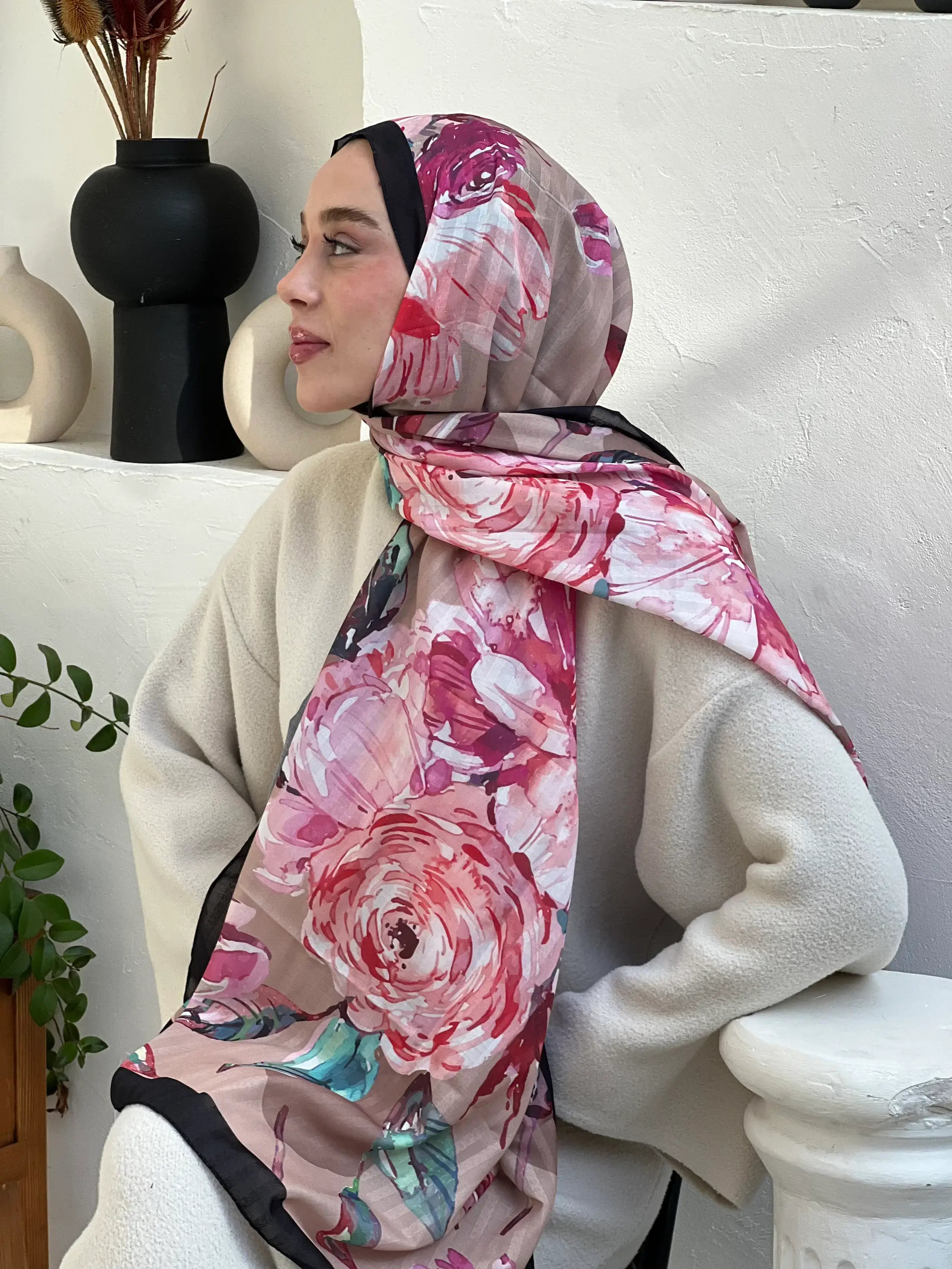 "Vizör tonlarında çiçek desenli, siyah kenarlı Acelya şal – modern bir ortamda beyaz kabanla kombinlenmiş zarif ve feminen stil."